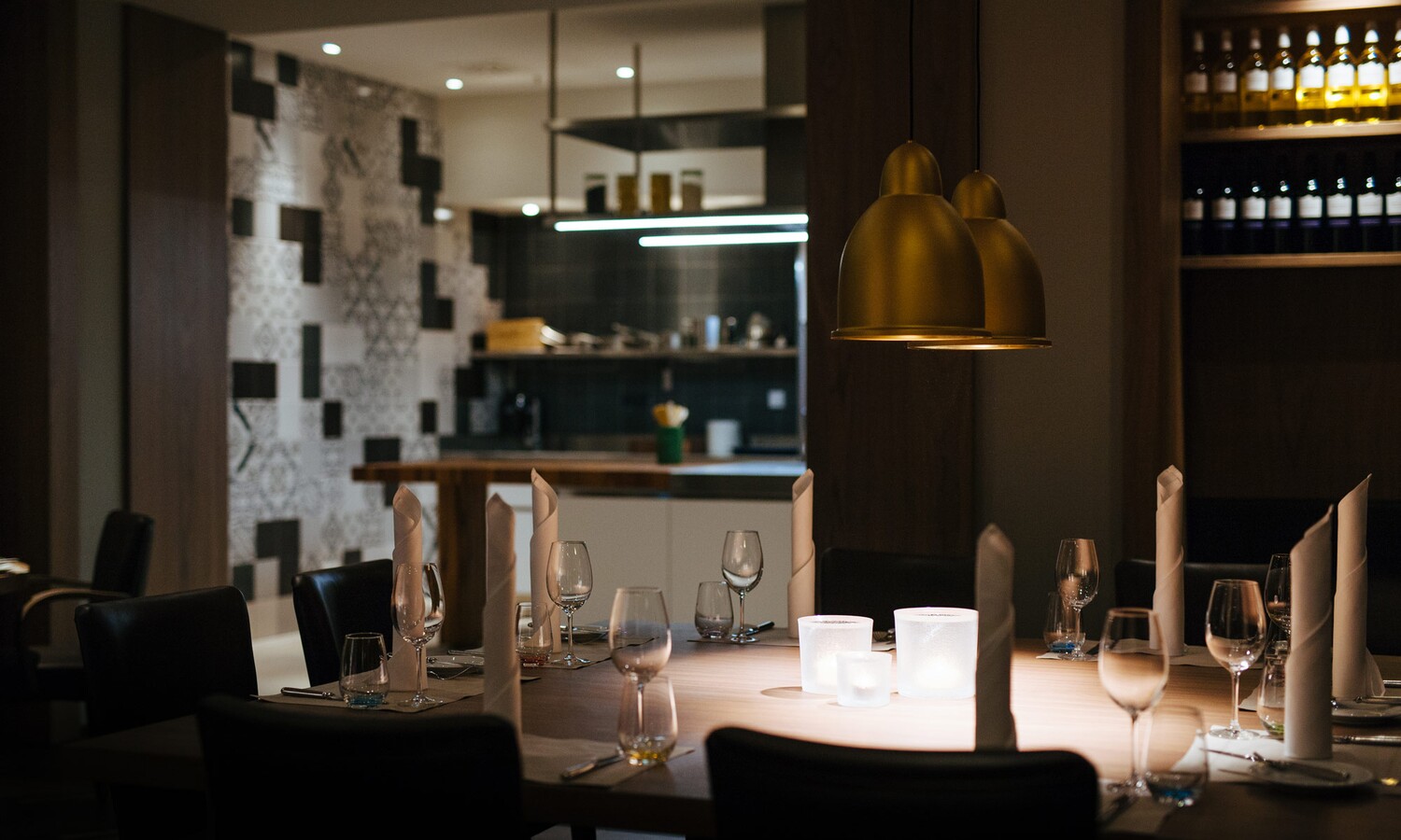 Eingedeckter Tisch im Vordergrund und Showküche im Hintergrund