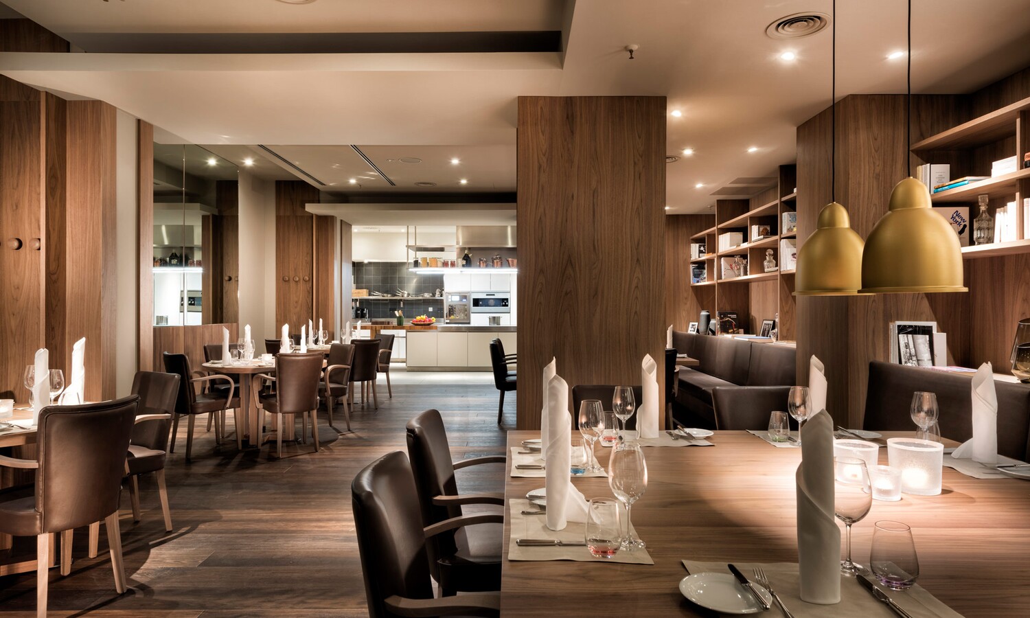 Eingedeckte Tische in Wohnzimmer-Atmosphäre und Showküche